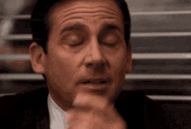 Michael Scott closes his eyes and gestures dismissively in an exasperated reaction.