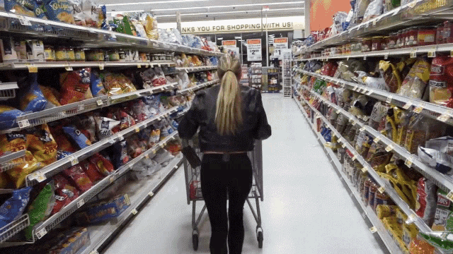 a woman pushing a shopping cart in a grocery store aisle with a sign that says thanks you for shopping with us