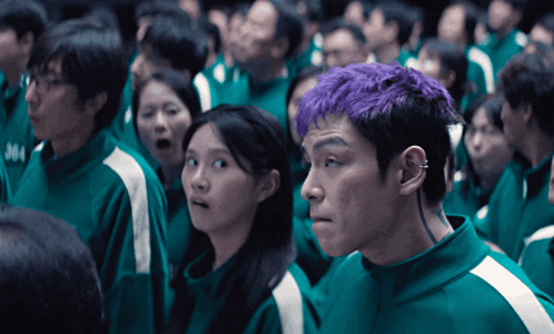 a man with purple hair is standing in a crowd of people