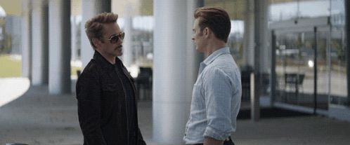 two men are standing next to each other and talking