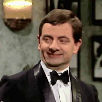 A man in a tuxedo gives a knowing, restrained smile.