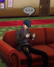 a man in a suit and hat is sitting on a red couch playing a video game .