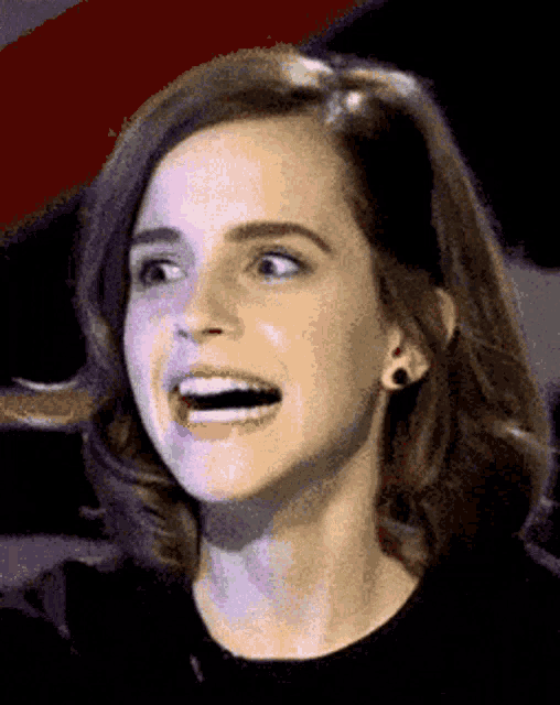 A woman gives a strained, uneasy smile in a dark setting.