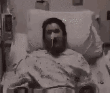 a man in a hospital bed with an oxygen mask on his face is being hit by a beam of light .