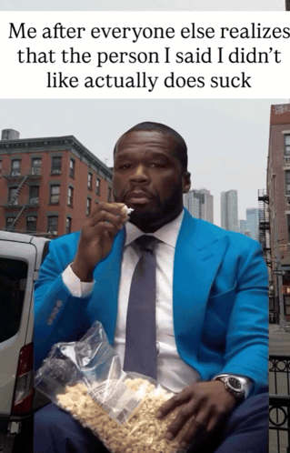 a man in a blue suit and tie is eating a bag of pop corn