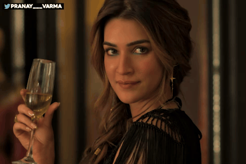 Kriti Sanon holds a champagne flute and gives a playful wink at a formal event.
