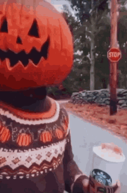a person with a pumpkin on their head holding a cup of coffee .