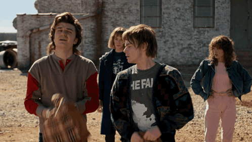 a group of people standing in front of a building with one wearing a shirt that says he fai