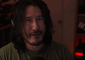 Markiplier smiles faintly in a dim room.