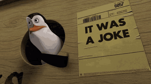 A penguin stands beside a sign reading “IT WAS A JOKE.”