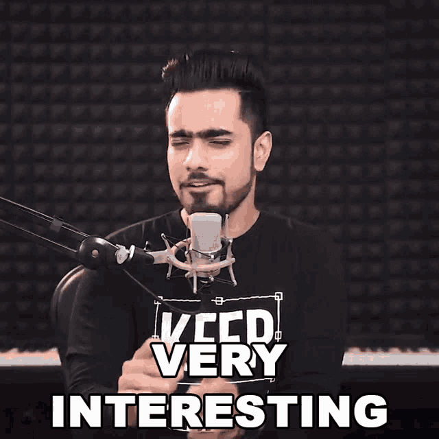 a man singing into a microphone with the words " very interesting " behind him