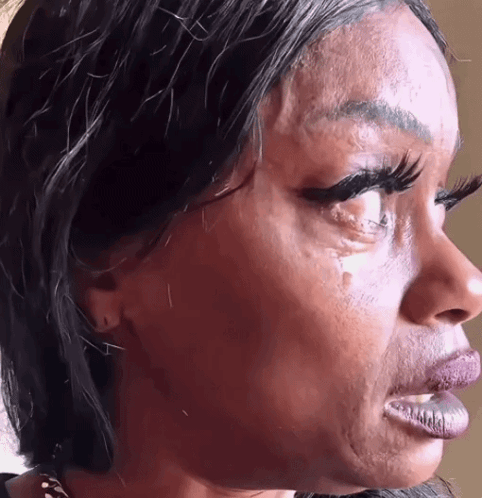 A woman cries with tears on her cheeks in a close-up profile.