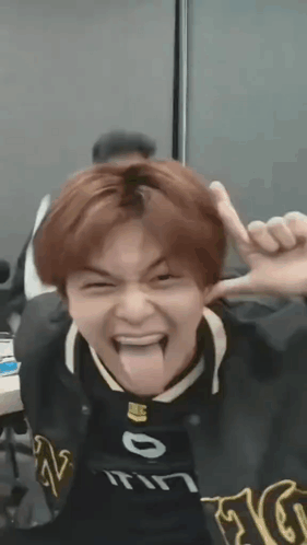 a young man is sticking his tongue out and making a funny face while wearing a black jacket .