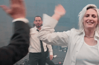 A woman in white reaches up to high five someone in a busy room.
