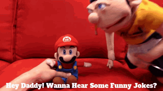 a mario puppet is sitting on a red couch next to another puppet