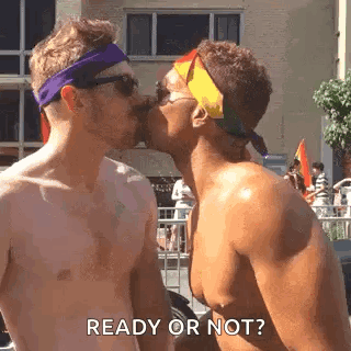 two men are kissing each other in front of a crowd at a parade .
