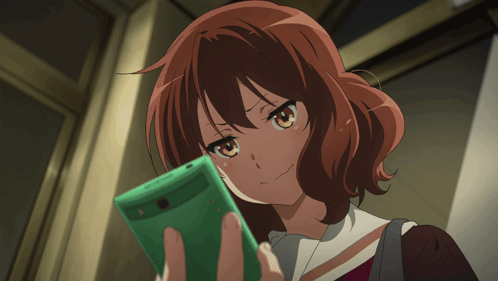 An anime girl grips a green smartphone with an angry expression.