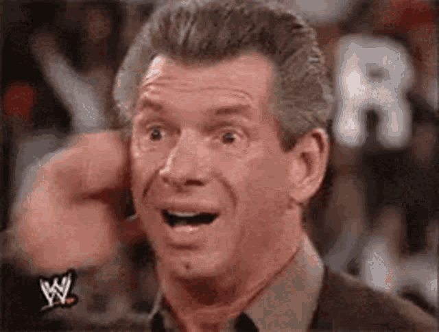 Vince McMahon laughs loudly with an exaggerated surprised expression.