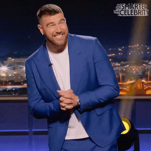 A suited man awkwardly smiles on a game-show stage.
