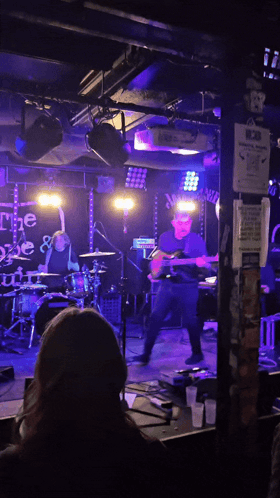 a man playing a guitar in front of a sign that says ' the gate '