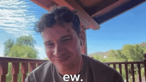 a man sitting on a balcony with the words ew written on his shirt