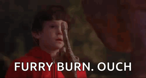 a boy in a red jacket is holding a candle in his hand and says furry burn ouch .