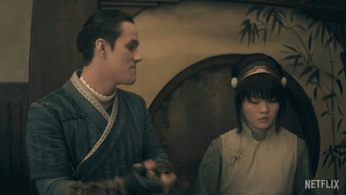 Two characters sit tensely in a dark Avatar: The Last Airbender scene.