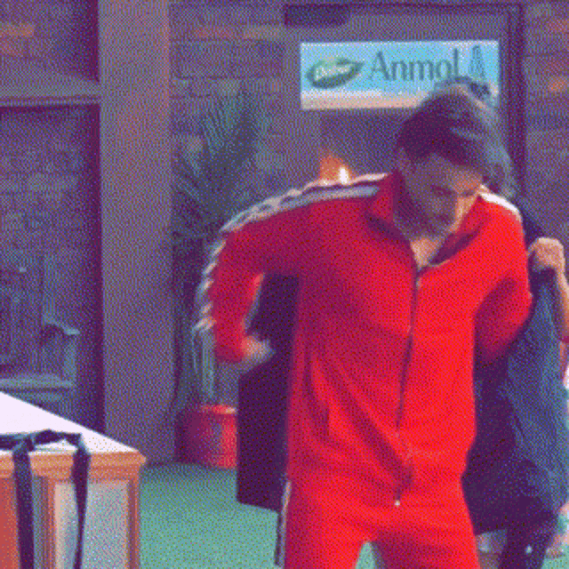 a man in a red jacket is hugging another man in front of a sign that says animal