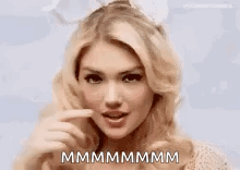 A blonde woman makes a playful kissy expression with “MMMMMMM” text.