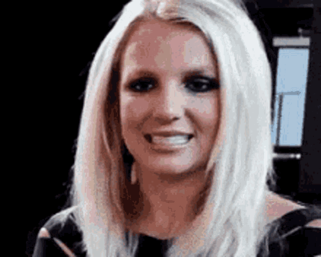 Britney Spears smiles awkwardly in a close-up reaction shot.