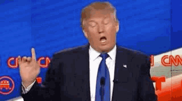 Donald Trump holds up one finger while speaking at a debate podium.