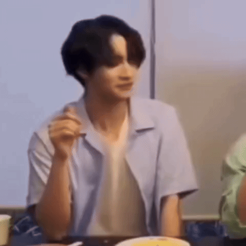 a man in a blue shirt is sitting at a table with a plate of food in front of him .