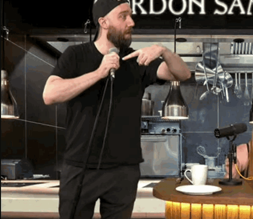 a man is speaking into a microphone in front of a sign that says gordon 's