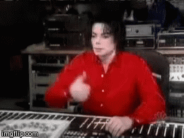 Michael Jackson sits at a keyboard and gives a thumbs up.