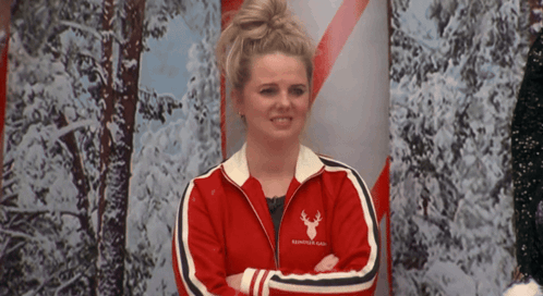 a woman with her arms crossed wears a red jacket with a reindeer on it