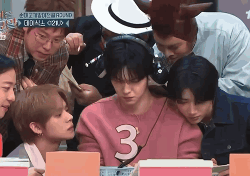 a group of young men are gathered around a man wearing a pink sweater with the number 3 on it