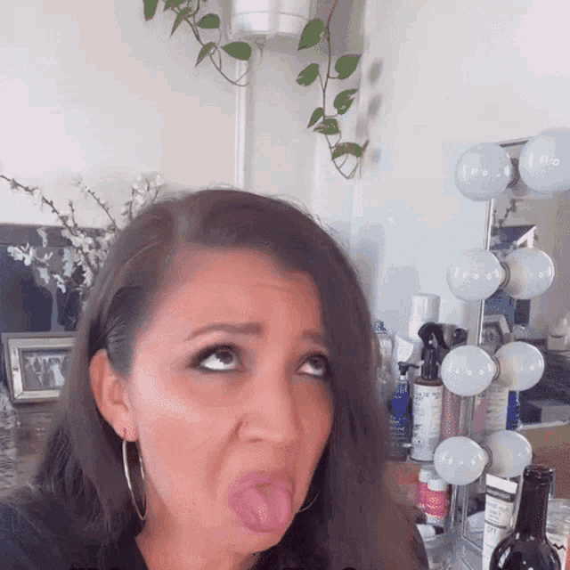 a woman is sticking her tongue out in front of a vanity with bottles of hair products