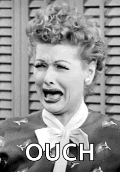 Lucy cries dramatically in a black-and-white close-up with “OUCH” text.