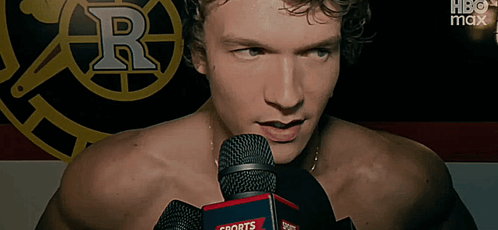 a shirtless man is speaking into a sports radio microphone