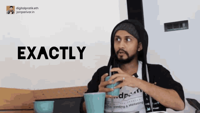 a man sitting at a table with a cup of coffee and the word exactly in the background