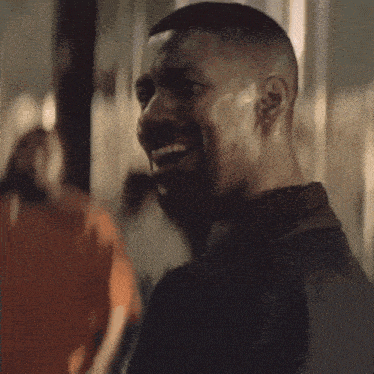 A man smiles knowingly in a dim party scene.