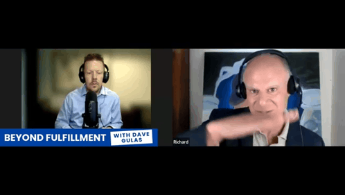 a man wearing headphones talks into a microphone while another man looks on