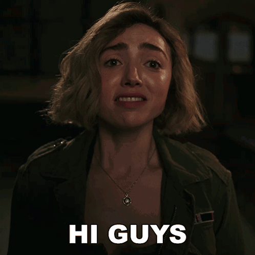 a woman says hi guys while wearing a green jacket