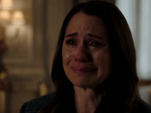 A woman cries intensely in a dramatic indoor scene.