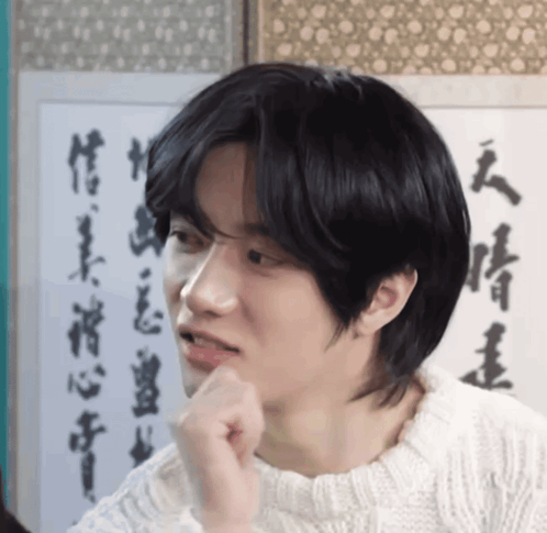 a man in a white sweater is looking at something