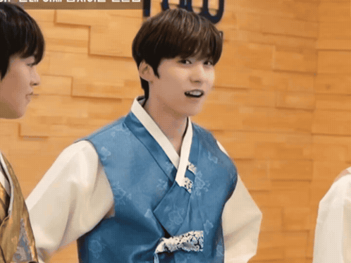 a boy in a blue and white kimono stands next to another boy in a white shirt