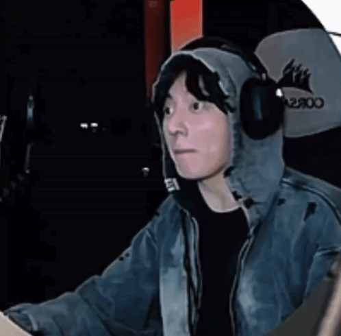 A streamer in headphones looks to the side from a gaming chair.