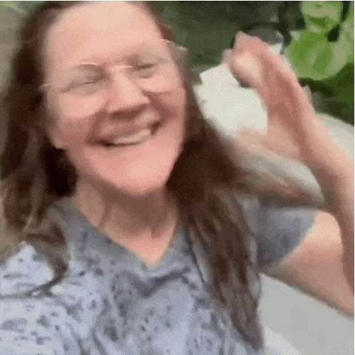 A woman laughs and waves her arms outdoors in a joyful reaction.