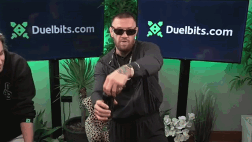 a man stands in front of a duelbits.com banner