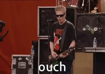 a man is playing a guitar and singing into a microphone on a stage with the word ouch in the background .
